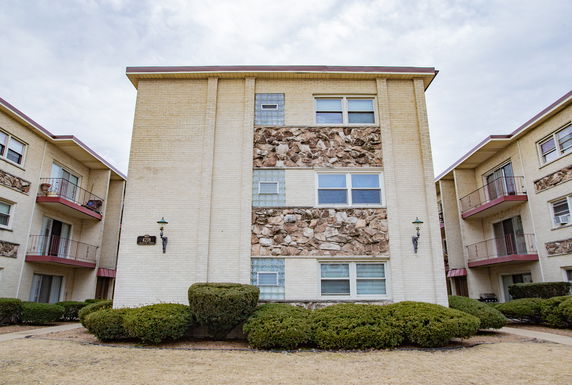 Front view of a multi-story apartment building with brick and stone facade.