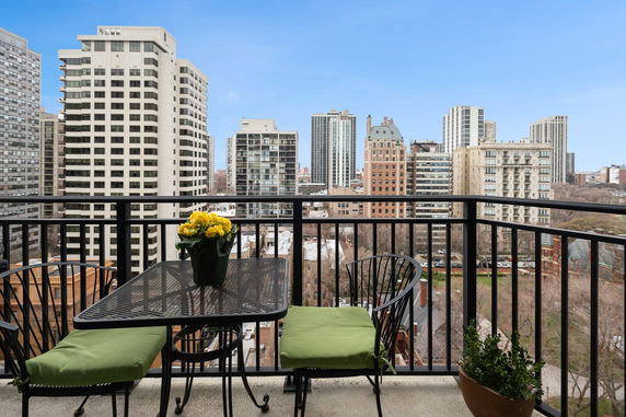 View of surrounding buildings from a balcony with outdoor seating.