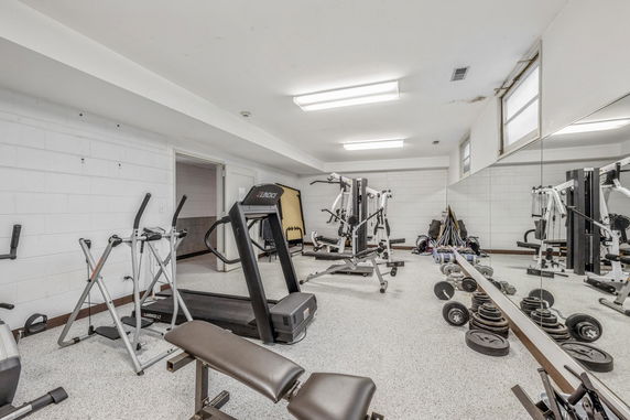 Indoor gym area with various exercise equipment and a large mirror on the wall.