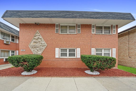 Front view of a two-story brick building with distinctive stone diamond pattern.