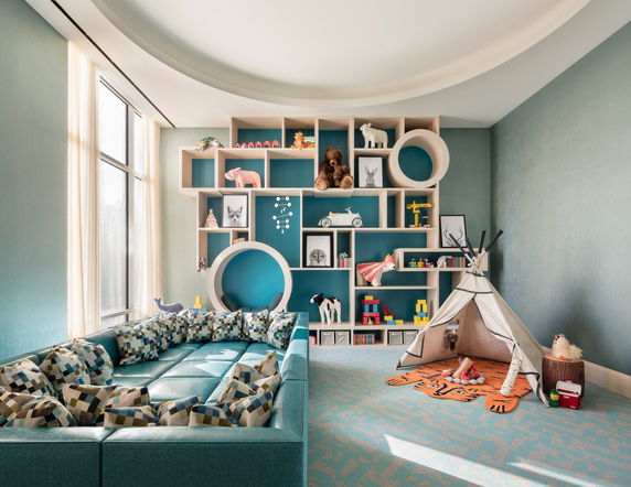 Indoor play area with a blue cushioned seating, decorative shelves with toys, and a small teepee tent.