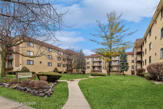 Front view of a multi-story apartment building with beige brick exterior.