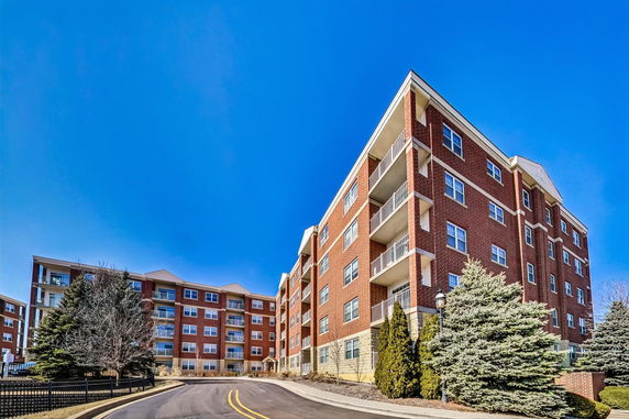 Front view of a multi-story brick apartment building with balconies.