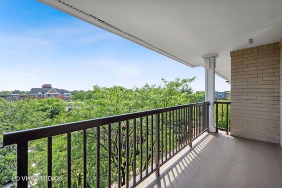 View from a balcony overlooking trees and a distant building.