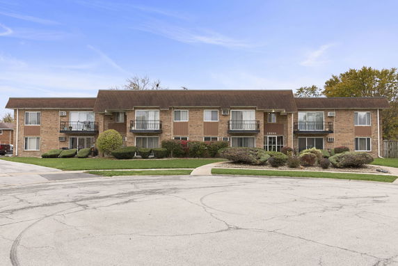 Front view of a two-story brick apartment building with balconies and air conditioning units.