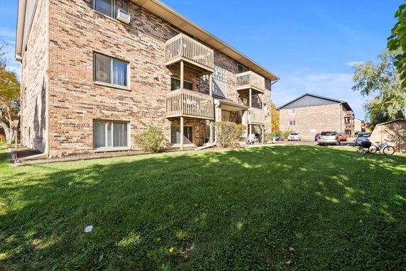 Front view of a three-story brick apartment building with balconies.