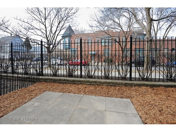 View of brick building with decorative metal fence and surrounding street.