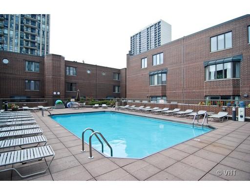 Outdoor swimming pool surrounded by a brick building with several lounge chairs.