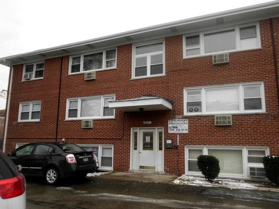 Front view of a three-story brick apartment building with multiple windows and a central entrance.