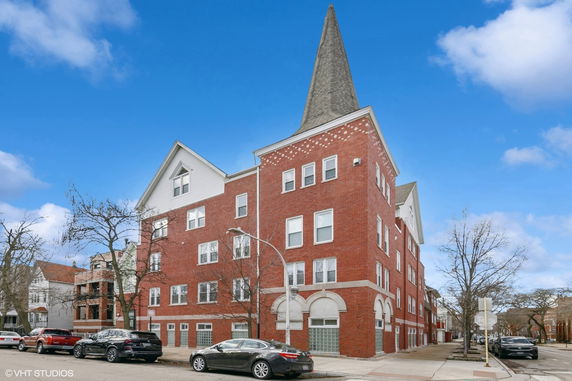 Front view of a multi-story brick building with pointed roof.