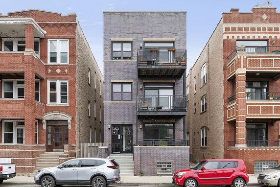 Front view of a three-story modern apartment building with balconies.