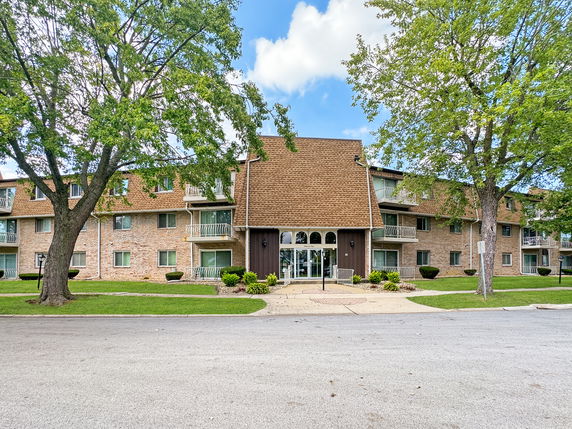 Front view of a multi-story apartment building with balconies and a triangular roof.
