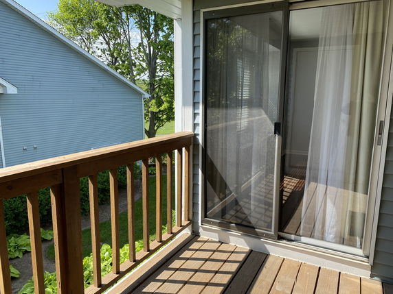 View from a wooden balcony overlooking a neighboring blue house.