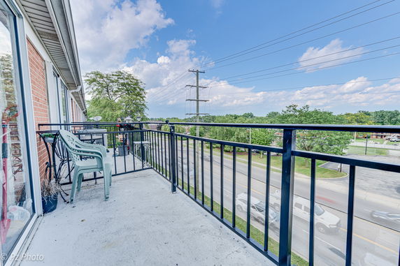 Balcony with a view of the street and distant trees.