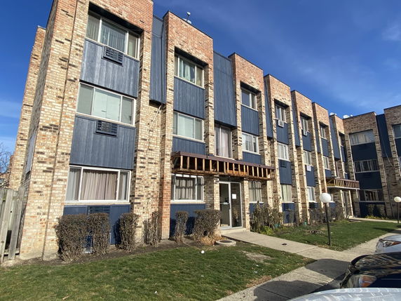 Front view of a brick apartment building with multiple floors and blue accents.