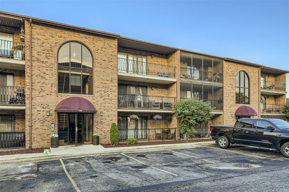 Front view of a three-story apartment building with balconies and arched windows.