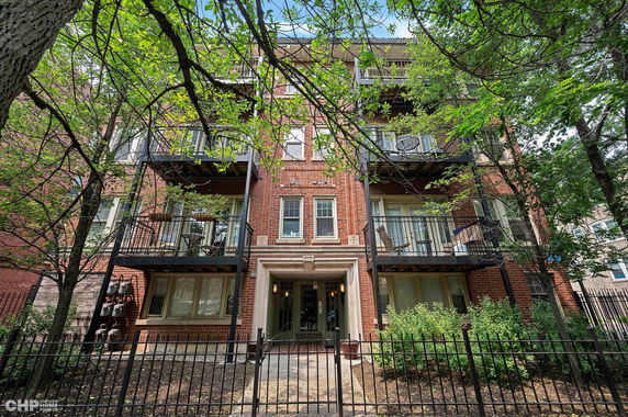 Front view of a multi-story brick apartment building with balconies.