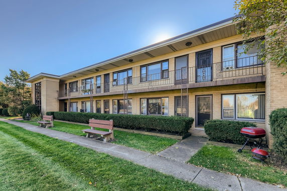 Front view of a two-story apartment building with balconies and multiple entrances.
