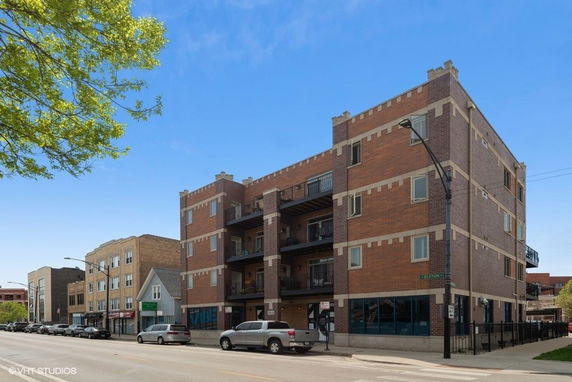 Front view of a four-story brick building with balconies and large windows.