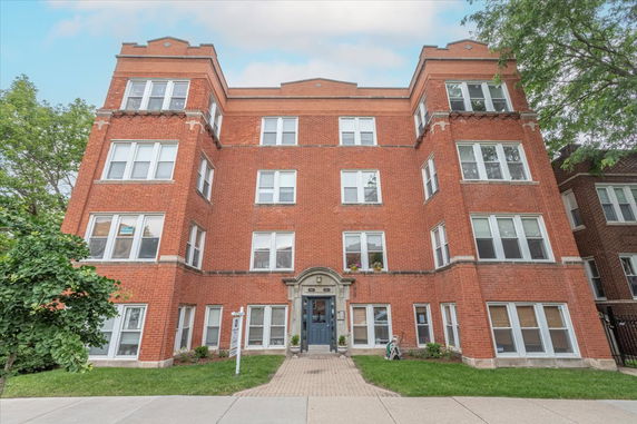 Front view of a multi-story brick apartment building with multiple windows.