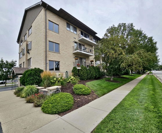 Front view of a multi-story building with balconies and landscaped surroundings.