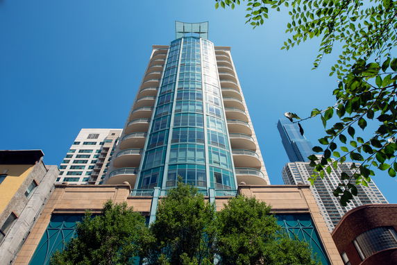 Front view of a tall modern building with glass facade and balconies.