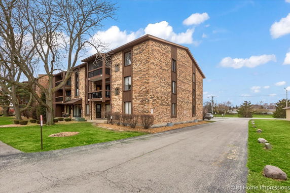 Front view of a three-story brick residential building with balconies.