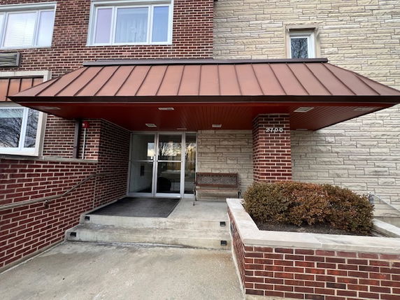 Front view of a brick building entrance with a metal awning.