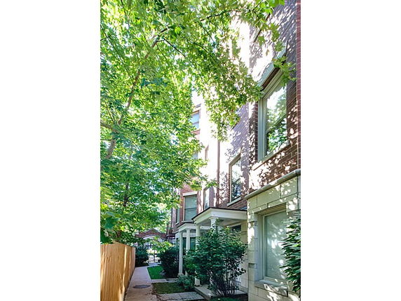 Side view of a multi-story residential building with large windows and surrounding greenery.