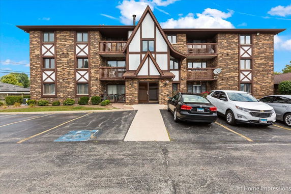 Front view of a three-story brick apartment building with a central gabled entryway.