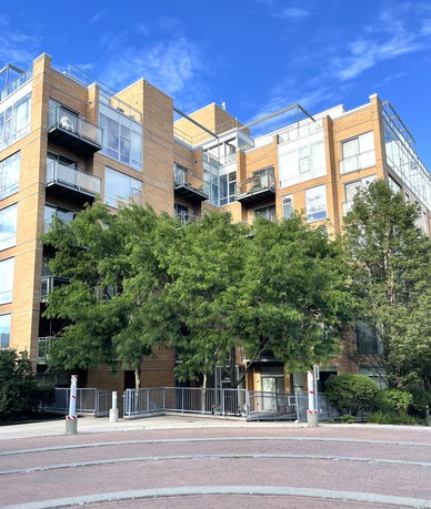 Front view of a multi-story apartment building with balconies and large windows.