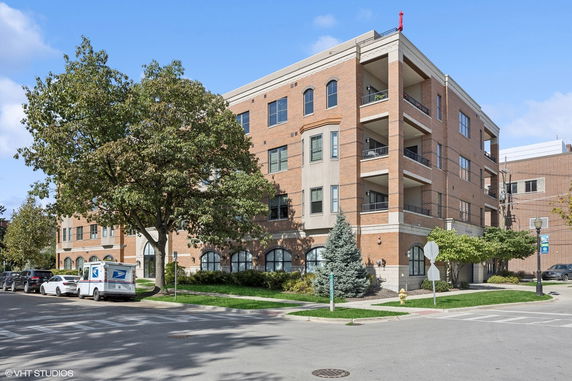 Front view of a multi-story brick apartment building with balconies.