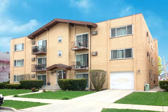 Front view of a multi-story apartment building with balconies and a garage.