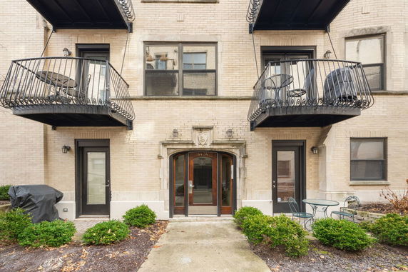 Front view of a brick building with balconies and glass door entrance.