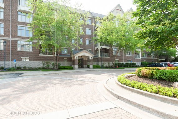 Front view of a multi-story residential building with a brick facade and arched entrance.
