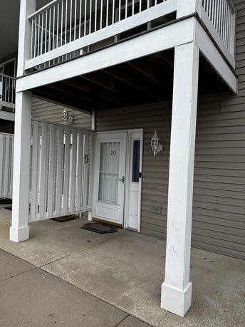 Front view of a two-story building with a porch area and upper balcony.