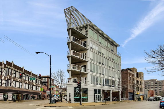 Front view of a modern multi-story building with large windows and balconies.