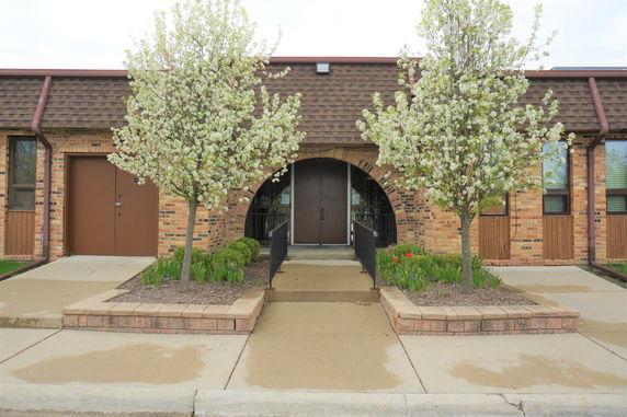 Front view of a brick building with arched doorway and two trees.