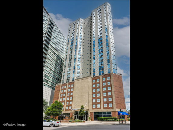 Front view of a tall multi-story building with a mix of brick and glass facade.