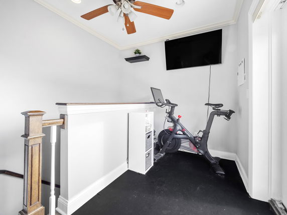 Indoor exercise area with a stationary bike and wall-mounted TV.