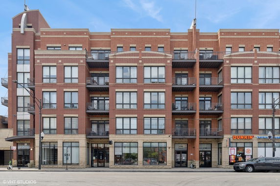 Front view of a multi-story brick building with commercial spaces on the ground floor.