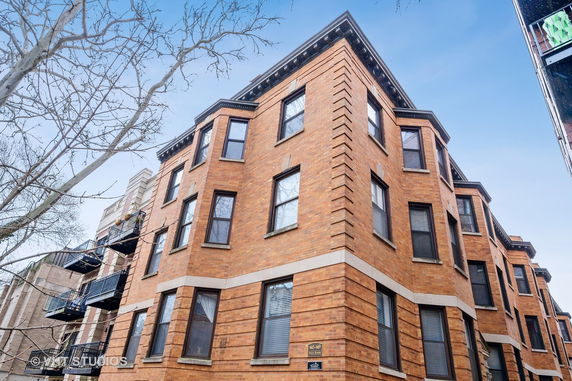 Front view of a multi-story brick building with several windows.
