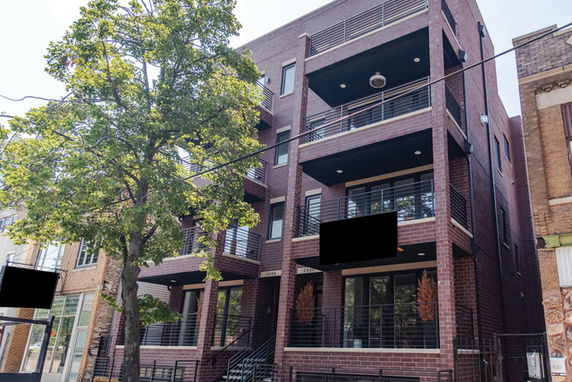 Front view of a multi-story brick building with balconies.