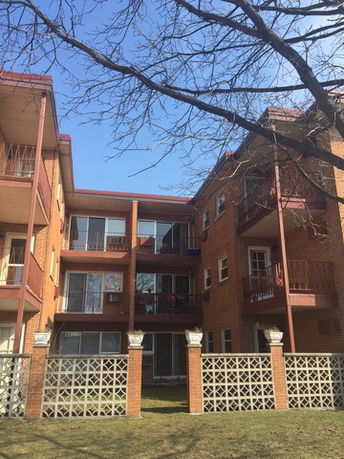 Front view of a multi-story brick building with balconies.