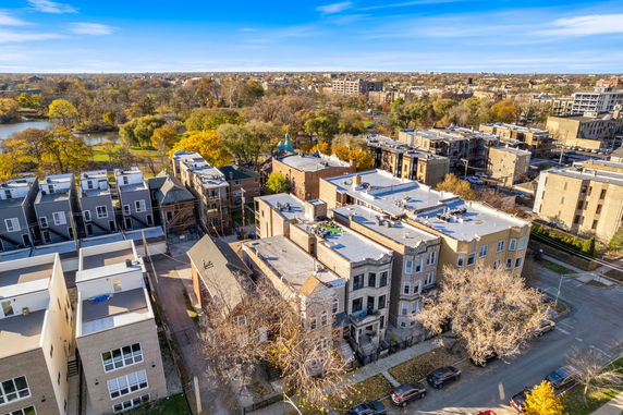 Aerial view of a residential area with multiple buildings and a park with trees in the background.
