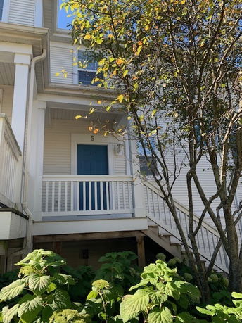 Front view of a multi-story house with a blue door and white railings.