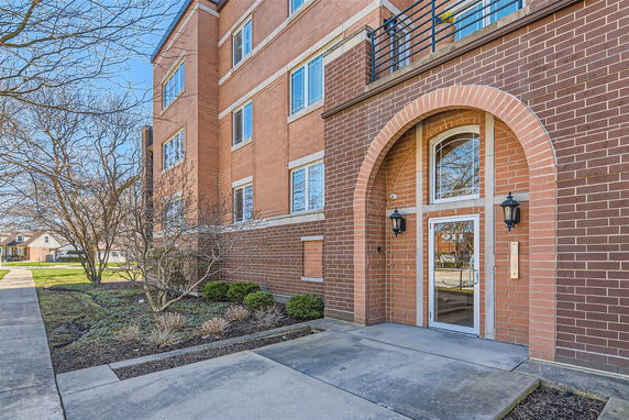 Front view of a multi-story brick building with arched entrance and multiple windows.