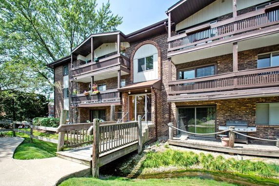 Front view of a multi-story building with balconies and a wooden bridge leading to the entrance.