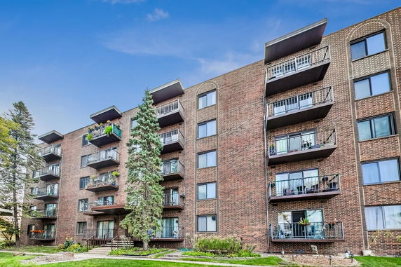 Front view of a multi-story brick apartment building with balconies.