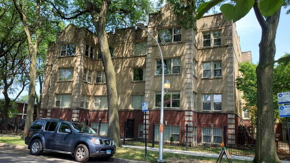 Front view of a multi-story apartment building with brick facade and large windows.